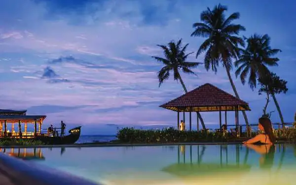 Karma Chakra’s waterfront pool, pavilion and moored boat at dusk