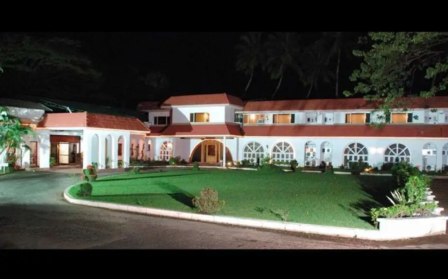 ATS Willingdon Hotel exterior and lawn at night, published in its owner-submitted Kerala Tourism profile; this does not show the assigned room or establish current condition.