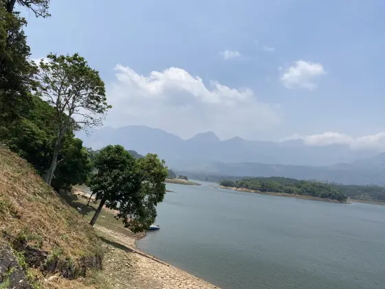 A moored boat beside Anayirankal reservoir, with cultivated slopes across the water.