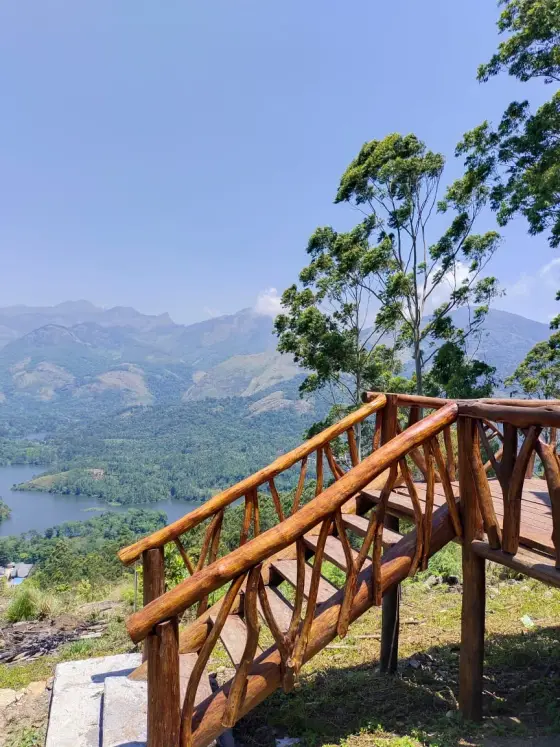 Wooden entrance steps and railings at Chundal A Frame Log House, with the reservoir beyond.