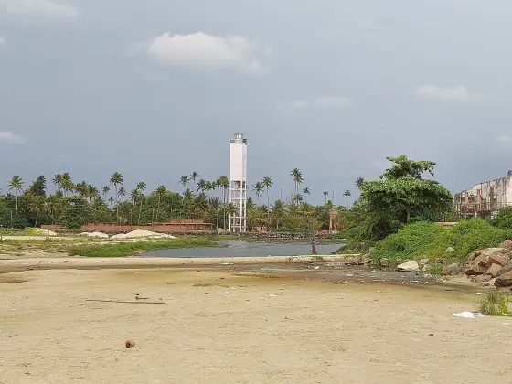 The tower seen from the beach across the channel — the square shaft, the open-legged base and the external stair are all visible from here, as is how little ground rises under it. The 1972 design for this site was a cylinder; the substrate would not take one.