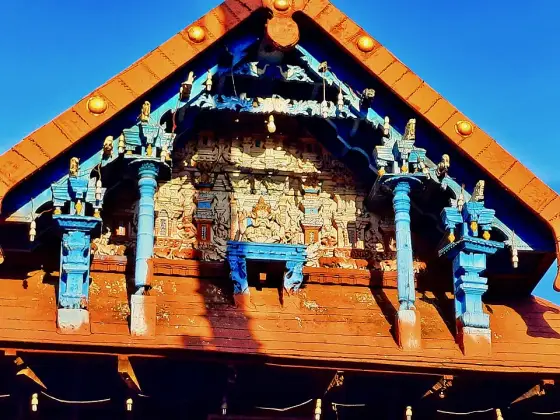 Carved and painted figures beneath a tiled temple gable.