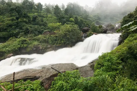 Water crossing broad rock ledges at Attukad Waterfalls.