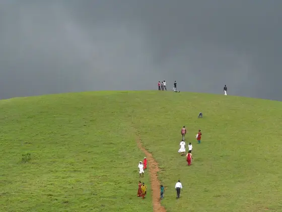 Visitors on a grassy slope beneath approaching clouds.