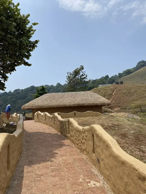 A paved path between the earthen walls and thatched structures.