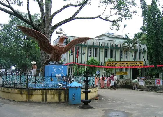 The Garuda statue beneath a large tree near the temple.