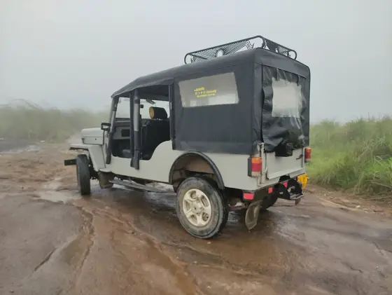 A canvas-covered jeep with yellow DTPC lettering stands on wet rock in mist at Ilaveezhapoonchira in 2021.