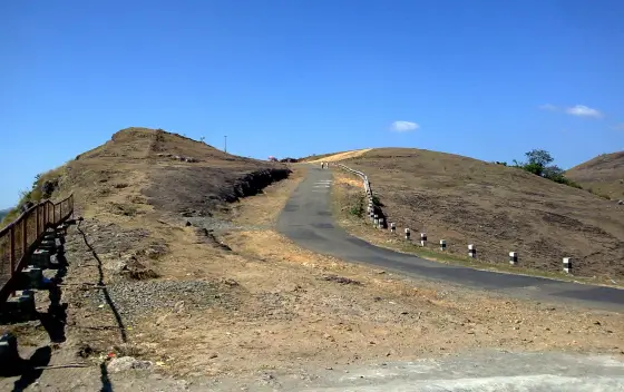 The road climbs beside railings through Parunthumpara’s open hill landscape.
