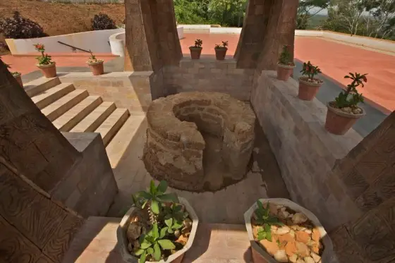 The circular laterite tomb inside the modern memorial pavilion.