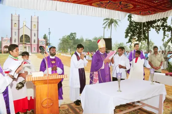 An outdoor Mass beneath a canopy, with clergy in purple vestments and Pallikkunnu Church behind.