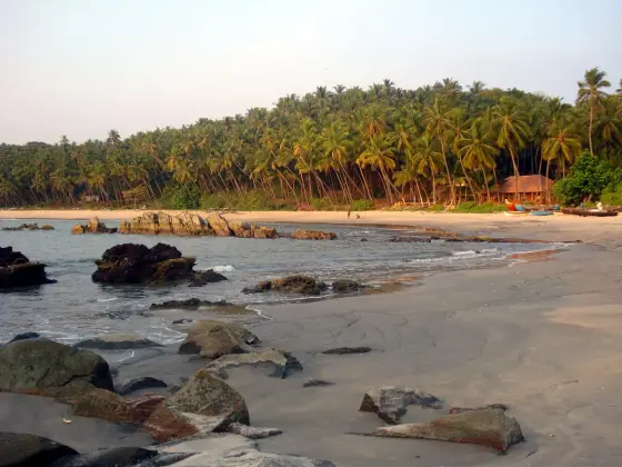 Boats and palms line a small sandy cove beside the Cherakallu rocks.