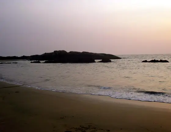 The low Cherakallu rock formations stand beyond the sand in fading light.