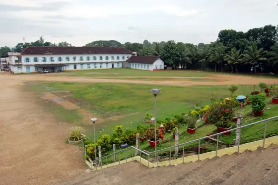 A field and long institutional building in Bharananganam’s educational neighbourhood; a context view, not the parish nave.