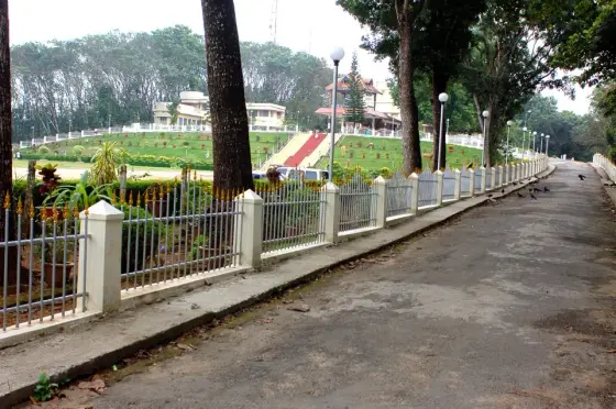 A paved garden path between devotional grottoes in the wider Bharananganam pilgrimage precinct.