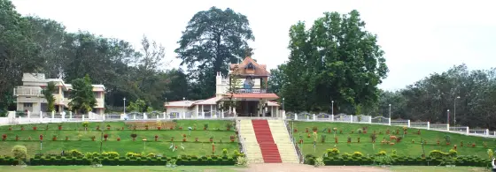 A landscaped devotional grotto in Bharananganam, reached by a red central stair.