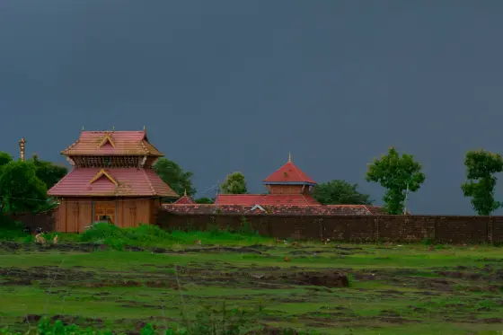 Vadukunda’s walled enclosure beneath a dark sky, with wet grass in the foreground.