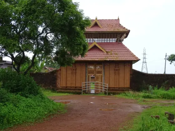 The named Vadukunda entrance gate: carved doors beneath a two-tier tiled roof, beside an earth approach.