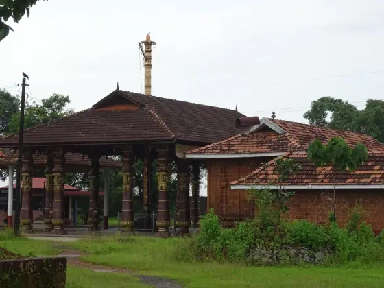The pillared porch and lower tiled roofs seen obliquely from outside the enclosure.
