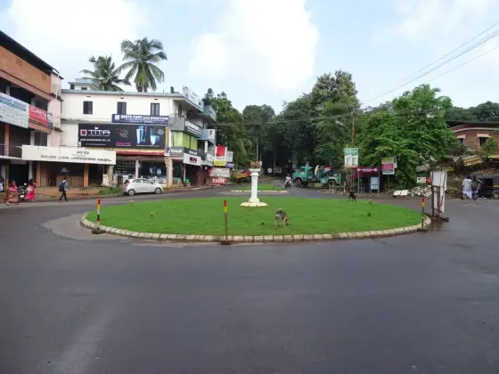 Madayi junction’s central grass island and surrounding shops, below the plateau approach.