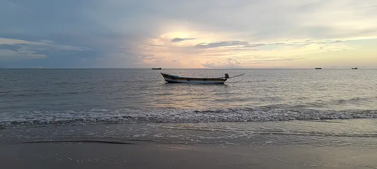 A fishing boat resting in calm shallow water off the low sandy shore at Point Calimere at dusk