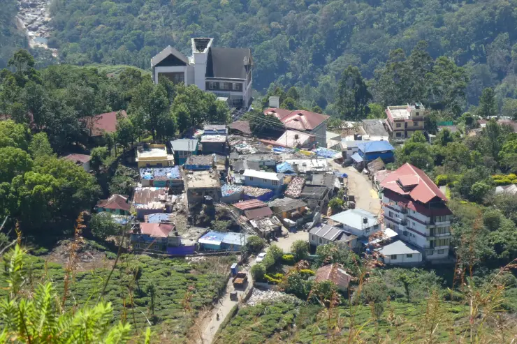 Colourful roofs and a curving road in Pothamedu village, surrounded by tea slopes.