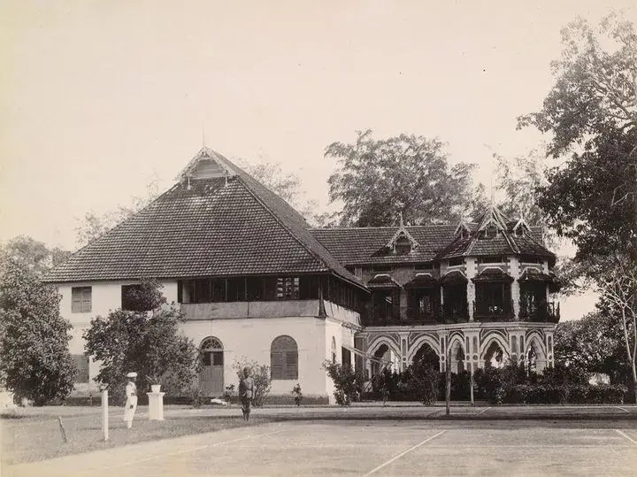 Period photograph of Bolgatty Palace, Kochi, showing the Dutch tiled block and a later ironwork verandah wing, with a tennis court in the foreground