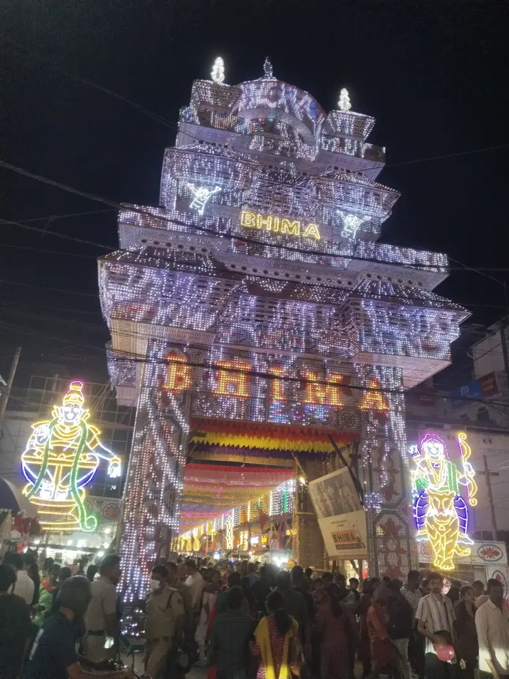 A towering illuminated gateway arch over a crowded street at night during the Mullakkal Chirappu festival