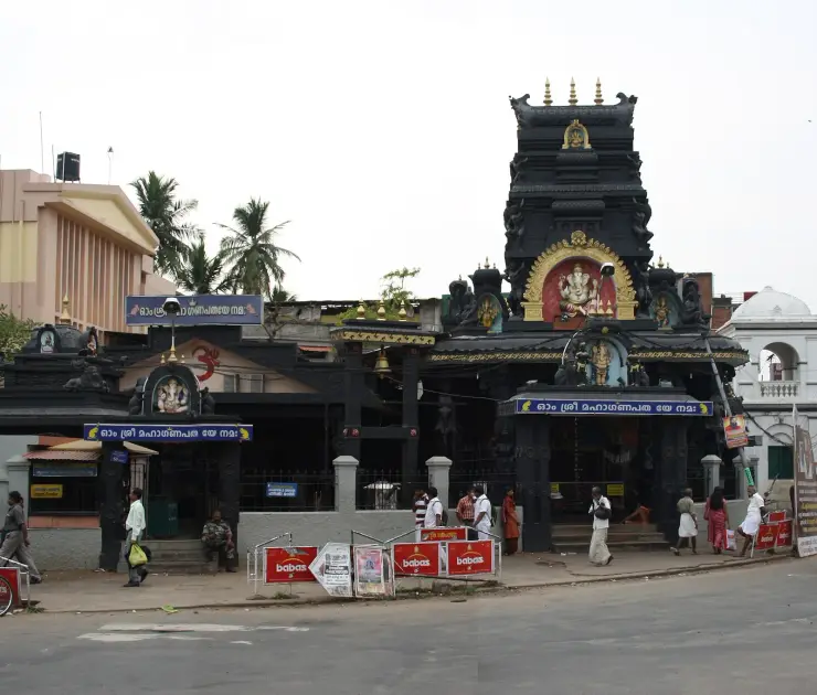 The Pazhavangadi Ganapathy Temple at East Fort, Thiruvananthapuram, with its dark tiered gopuram and Malayalam boards reading Om Sri Mahaganapataye Namah