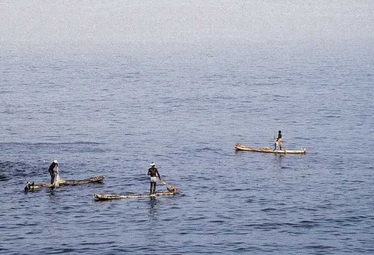 Three kettumaram log rafts worked by standing fishermen on calm water off Kovalam