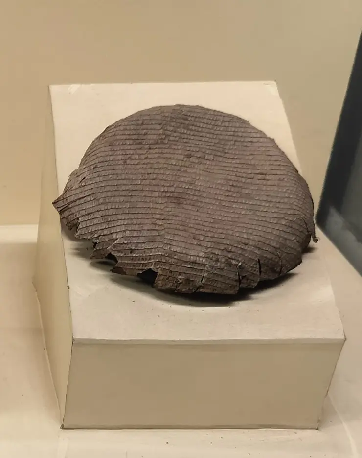 The Chandravalayam displayed on a white plinth at Koyikkal Palace — a shallow domed disc with fine concentric ridging and a chipped rim