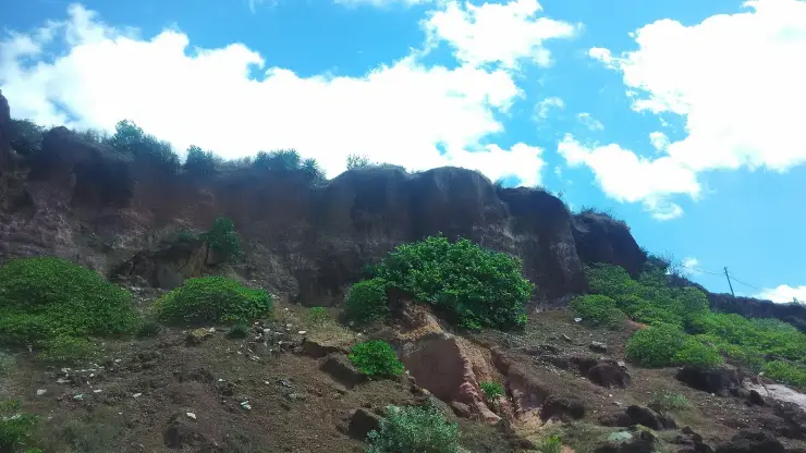 The layered face of the Varkala cliff seen from the beach, red laterite over paler sandstone with slumped material at the base