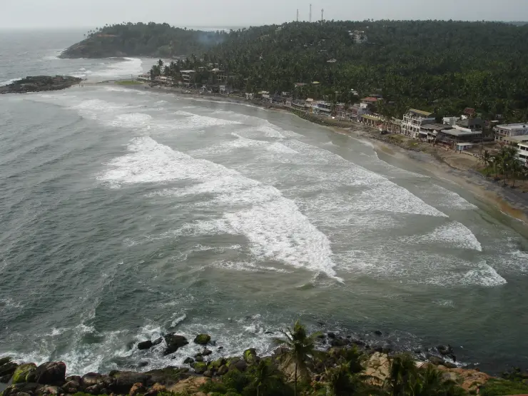 Lines of surf breaking along the full length of Lighthouse Beach at Kovalam, seen from above