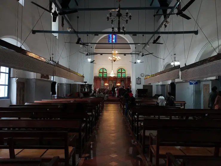 The bare whitewashed nave of St Francis Church, Kochi, with wooden punkah frames slung above the pews
