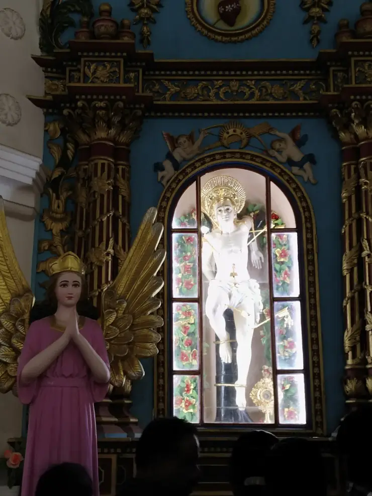 The white statue of St Sebastian bound to a dark post and pierced with gilt arrows, inside a glazed arched case set in a carved and gilded baroque reredos on a deep teal ground
