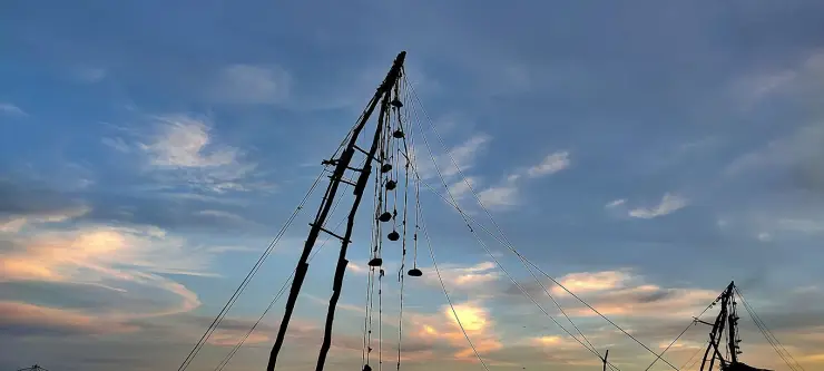 The apex of a Chinese fishing net against an evening sky, with counterweight stones hanging on ropes