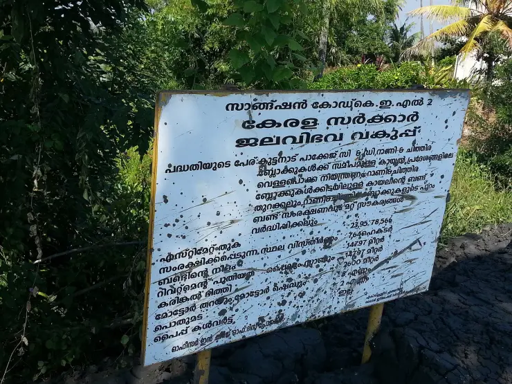 A weathered Kerala Water Resources Department project board at R Block, lettered in Malayalam with a list of quantities