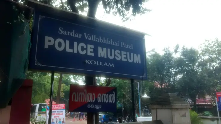 A blue signboard reading Sardar Vallabhbhai Patel POLICE MUSEUM KOLLAM, with a red and blue board below it reading Vanitha Cell in Malayalam