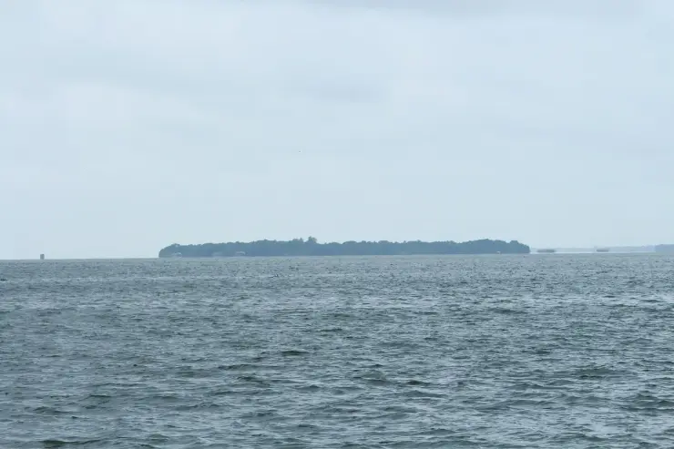Pathiramanal island seen as a low wooded line across the open water of Vembanad Lake under an overcast sky