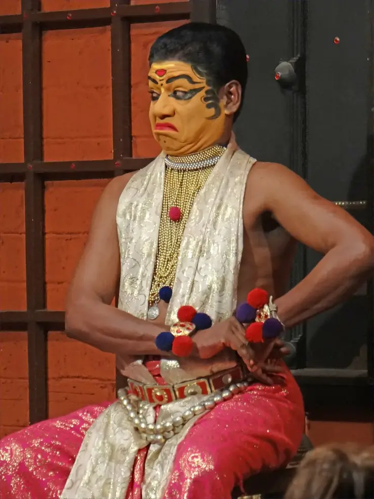 A Kathakali performer in full make-up and costume on a small stage in Kochi, mid-expression