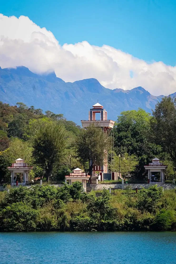 The watch tower and pavilions at Neyyar Dam seen across the reservoir, with the Agasthyamala ridge behind