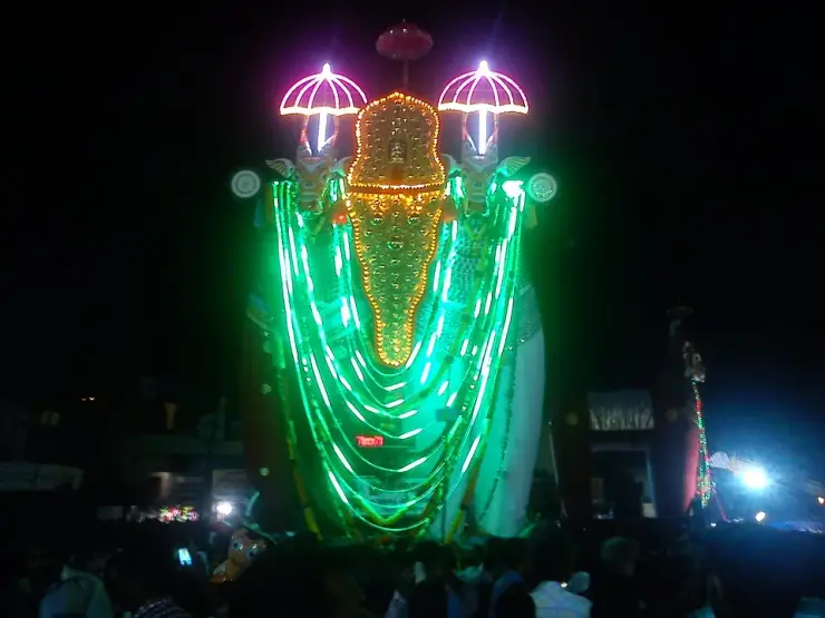 Towering straw-and-cloth effigy bulls on wheeled frames, lit at night, assembled on the temple ground at Oachira.