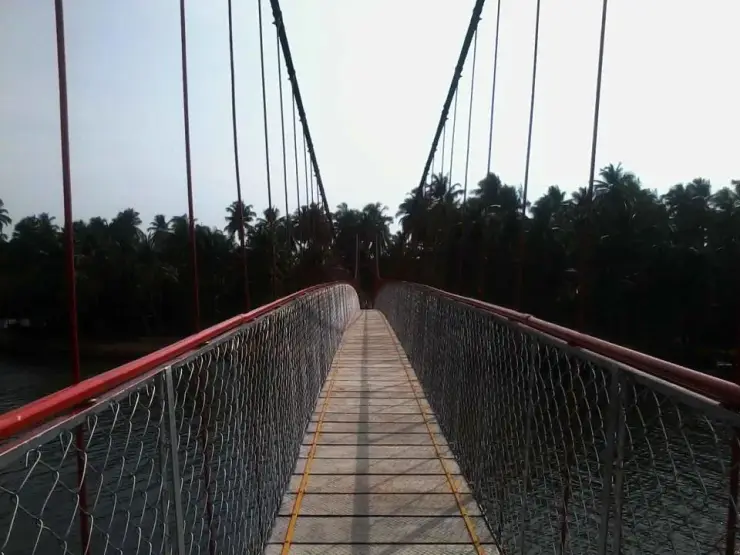 A red suspension footbridge over a river at Thookkupalam in Idukki