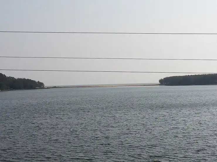 Looking west down the Thottappally channel towards the Arabian Sea, with a continuous sand bar closing the mouth across the frame