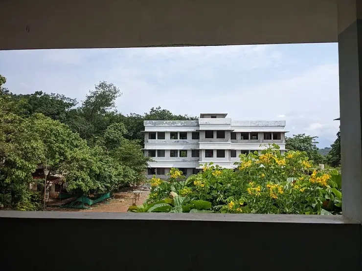 The Aralam Farm Higher Secondary School, a long white building standing among trees on the farm land in Kannur