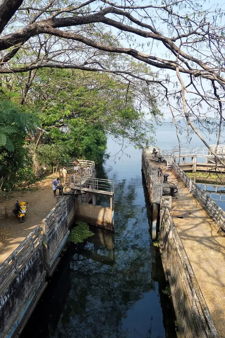 Looking down into a navigation lock chamber at the Thanneermukkom bund, with stone walls, timber gates and hand-wound gear on the walkway