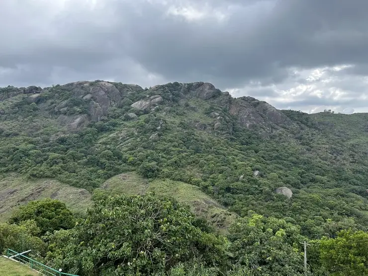 Rocky green Vagamon ridge beneath dark rain clouds