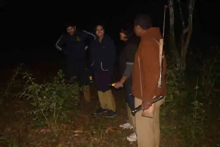 Visitors with torches gather around an armed guide for a night-walk briefing at Periyar.