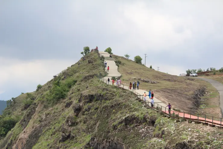 Visitors follow steps and metal-railed sections across Parunthumpara’s grassy viewpoint slope