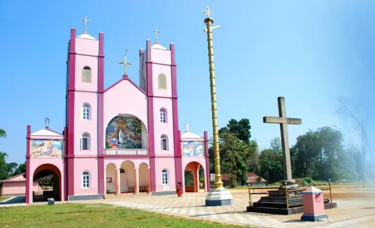 An archival view shows Pallikkunnu’s pink twin-towered façade, golden flagstaff and freestanding stone cross.