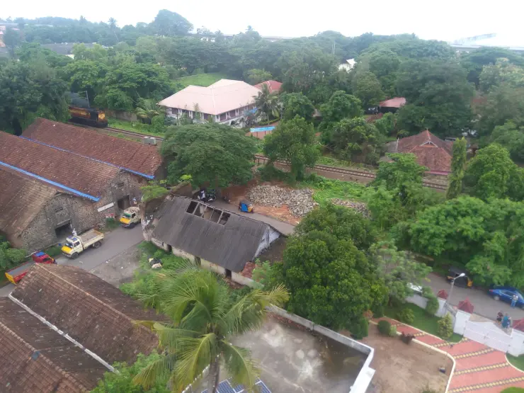 A train passes between roofs and greenery in a 2017 view photographed from Alappuzha Lighthouse.